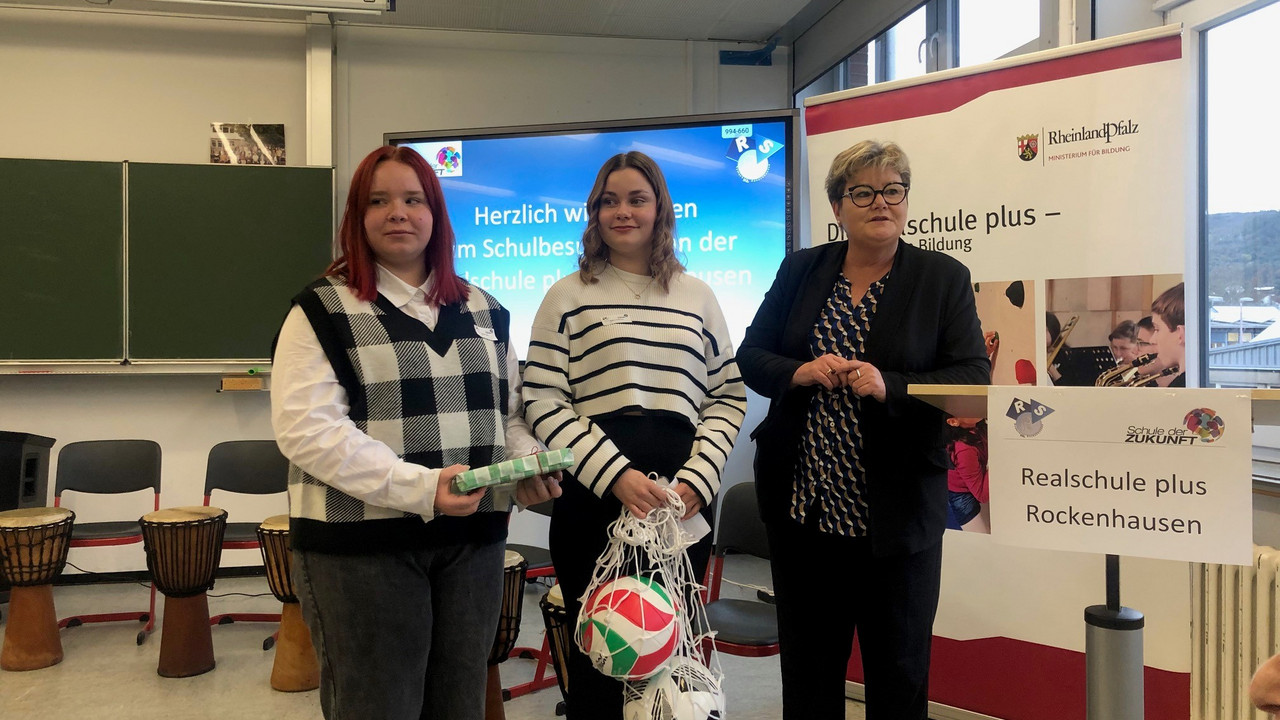 Staatssekretärin Brück überreicht Geschenke an zwei Schülerinnen.