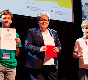 Hier sehen Sie Bildungsstaatssekretärin Bettina Brück mit den beiden Sonderpreissiegern und gleichzeitigen Erstplatzierten im Themenbereich Arbeitswelt Jonathan und Leopold Kammerlander.