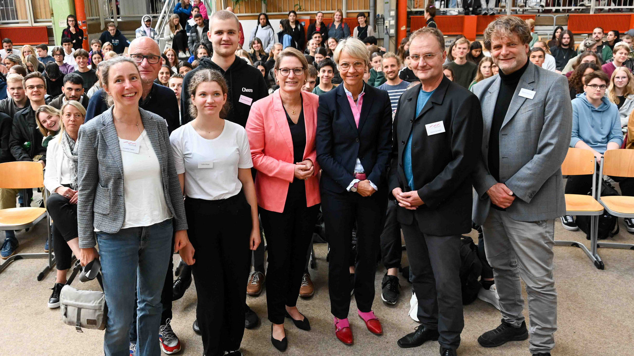 Auf dem Foto sind Die rheinland-pfälzische Bildungsministerin Dr. Stefanie Hubig neben der nordrein-westfälischen Bildungsministerin Dorothee Feller. Daneben Vertreterinnen und Vertreter der Bielefelder Schulgemeinschaft zu sehen. 